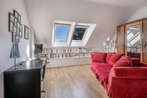 a living room with a red couch and books at A 150m de la plage, jolie maison avec jardin pour 10 in Saint-Sébastien