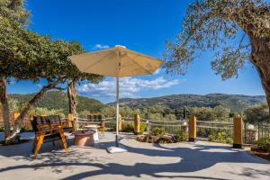 a patio with a bench and an umbrella at Villa Angelo ΙΙ in Paleokastritsa