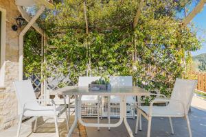 a table and chairs on a patio with a green wall at Villa Angelo ΙΙ in Paleokastritsa