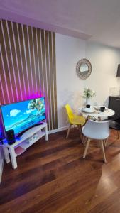 ein Wohnzimmer mit einem Tisch und einem TV sowie einem Tisch und Stühlen in der Unterkunft Cozy 1 bedroom apartment, Sheffield city center, free wifi in Sheffield