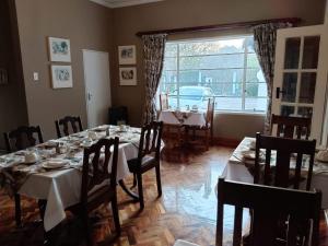 Un comedor con mesa y sillas y una ventana. en The Riverhouse Guesthouse, en Estcourt