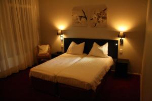um quarto de hotel com uma cama com lençóis brancos e almofadas em Stadshotel Ootmarsum em Ootmarsum