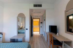 a room with a bed and a desk and a television at Centro Turistico Akiris in Nova Siri Marina