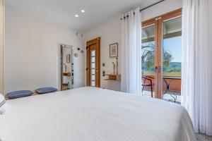 a white bedroom with a bed and a balcony at Villa Angelo ΙΙ in Paleokastritsa