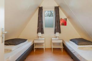 two beds in a room with a window at Boompieper I Beautiful family chalet with garden in Zwiggelte