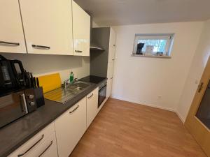 Una cocina con gabinetes blancos y un fregadero. en Haus Ostseesprung - Fewo Valentina im Souterrain mit Terrasse und gem Garten, en Bad Doberan