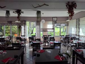 a dining room with tables and chairs and windows at Le Permayou in Accous