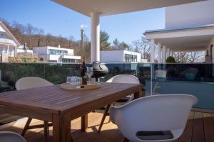 a wooden table and white chairs on a patio at Südstrandquartier - Ferienwohnung Cor in Ostseebad Sellin