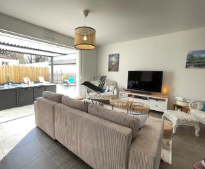 a living room with a couch and a tv at Les Ganivelles - Belle maison neuve avec extérieur in La Tremblade