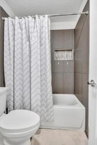 a bathroom with a tub and a toilet and a shower curtain at Bermuda Bungalow in Ponte Vedra Beach +22 photos