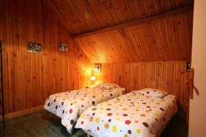 two beds in a room with wooden walls at Les Noisettes Sauvages proche Etretat in Villainville