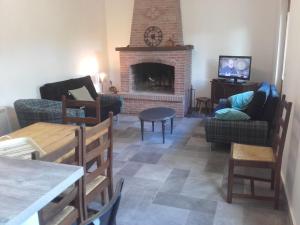 a living room with a fireplace and a table and chairs at Les Noisettes Sauvages proche Etretat in Villainville