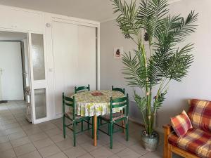 a table and chairs in a living room with a plant at Tamaris 26 in Quend-Plage