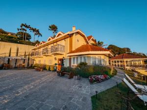 坎波斯杜若尔当Pousada Ville Le Mont - Campos do Jordao的一座大型黄色房子,前面设有一个庭院