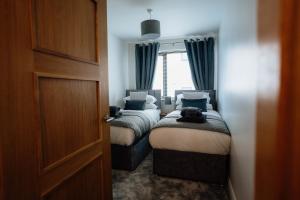 two beds in a small room with a window at MD Stays in Portstewart