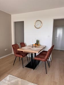 a dining room table with chairs and a clock on the wall at Fewo Strandbrise in Eckernförde
