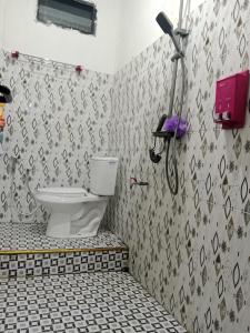 Un baño con inodoro y un teléfono en la pared. en Homestay komodo, en Komodo