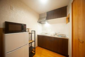 a small kitchen with a refrigerator and a sink at beppu turu 鶴 in Beppu