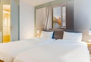 2 weiße Betten in einem Zimmer mit Fenster in der Unterkunft B&B HOTEL Chatellerault in Châtellerault + 44 Fotos