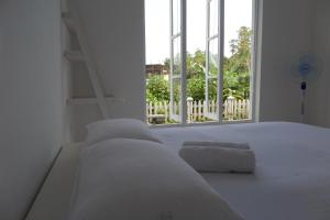 Un dormitorio con una cama blanca con una ventana. en White Villa Ambalangoda, en Ambalangoda