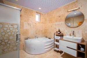 a bathroom with a tub and a sink and a mirror at Cappadocia Essa Orange Stone House in Nevsehir +10 photos