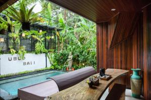 a room with a table and a swimming pool at Tamyang Ubud Villas in Ubud