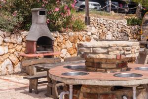 ein Außengrill mit Tischen und einer Steinmauer in der Unterkunft Eurocamp mobilhomes at Simuni in Šimuni