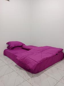 Una cama púrpura sentada en una habitación blanca en Homestay komodo, en Komodo