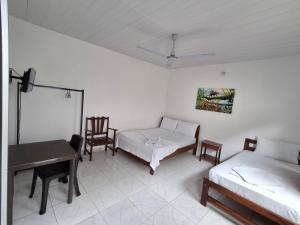 a room with two beds and a table and chairs at Heliconias Hotel in Leticia