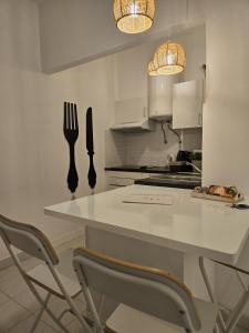 a kitchen with a white counter with two chairs and a table at Peixe and Barco Studio's in Vilamoura