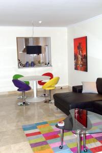 sala de estar con sofá negro y sillas coloridas en Luxe appartement Las Palmeras Calahonda, en Sitio de Calahonda