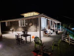 una pequeña casa con mesa y sillas por la noche en The Plum Castle, en Kodaikanal