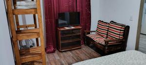 a room with two bunk beds and a tv and a chair at Lo de tina in Florencio Varela