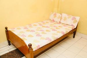 a small bed with pink and white sheets and pillows at DKS Lodge in Vellore