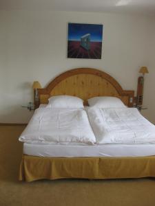 Una cama con sábanas blancas y almohadas en un dormitorio. en Ferienwohnung Marie, en Feldberg
