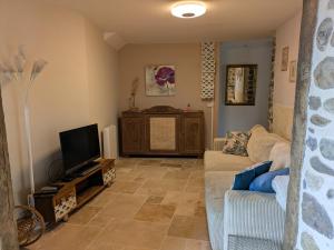 a living room with a couch and a tv at Les pierres qui parlent in Précilhon