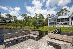Un muelle de madera con dos bancos y una casa. en 30A Pelican Watch, en Santa Rosa Beach