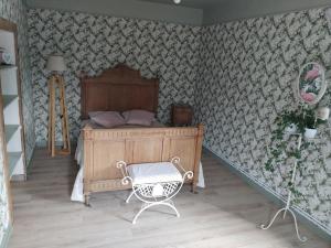 a bedroom with a wooden bed and a chair at Charmante maison avec cheminée, grand jardin et boxe chevaux in Saint-Hilaire-sur-Helpe