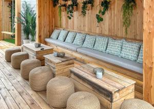 a wooden patio with a couch and some tables and stools at Whitehouse Holiday Park in Abergele