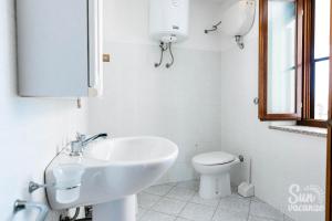 a white bathroom with a sink and a toilet at Malamuri 5 sun vacanze in Budoni