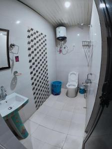 a white bathroom with a toilet and a sink at Golden Oak Villa Mussoorie in Rājpur