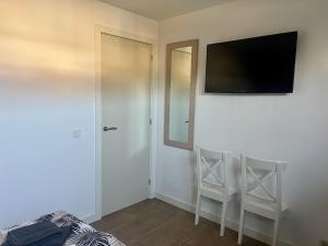 a bedroom with a tv on the wall and two chairs at BeachHouse AAN ZEE in Noordwijk aan Zee