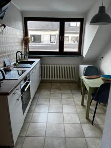 eine Küche mit einem Waschbecken, einem Tisch und einem Fenster in der Unterkunft Schöne DG - Wohnung in Bonn in Bonn + 6 Fotos