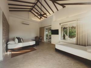a large room with two beds and a television at SABAI Beach Hotel in Barú