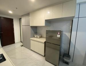 a kitchen with white cabinets and a refrigerator at Sky House BSD in Samporo