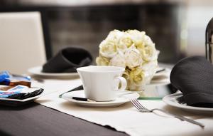 einen Tisch mit einer Kaffeetasse und einem Strauß weißer Rosen in der Unterkunft Gabri Park Hotel in San Salvo
