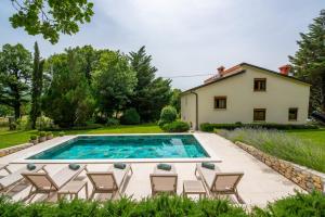 basen z krzesłami i dom w tle w obiekcie House Iva- peacefull getaway w mieście Boljun