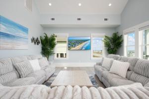 a living room with white couches and windows at Fins & Feathers home in Gilchrist