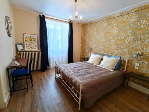 a bedroom with a bed and a wall with floral wallpaper at Domaine de la Moselle in Saint-Maurice-sur-Moselle