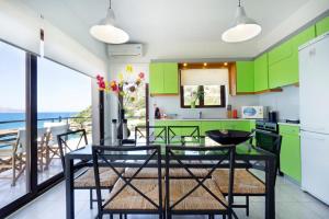 a kitchen with green cabinets and a table with chairs at Ostria Seaside House in Almyrida